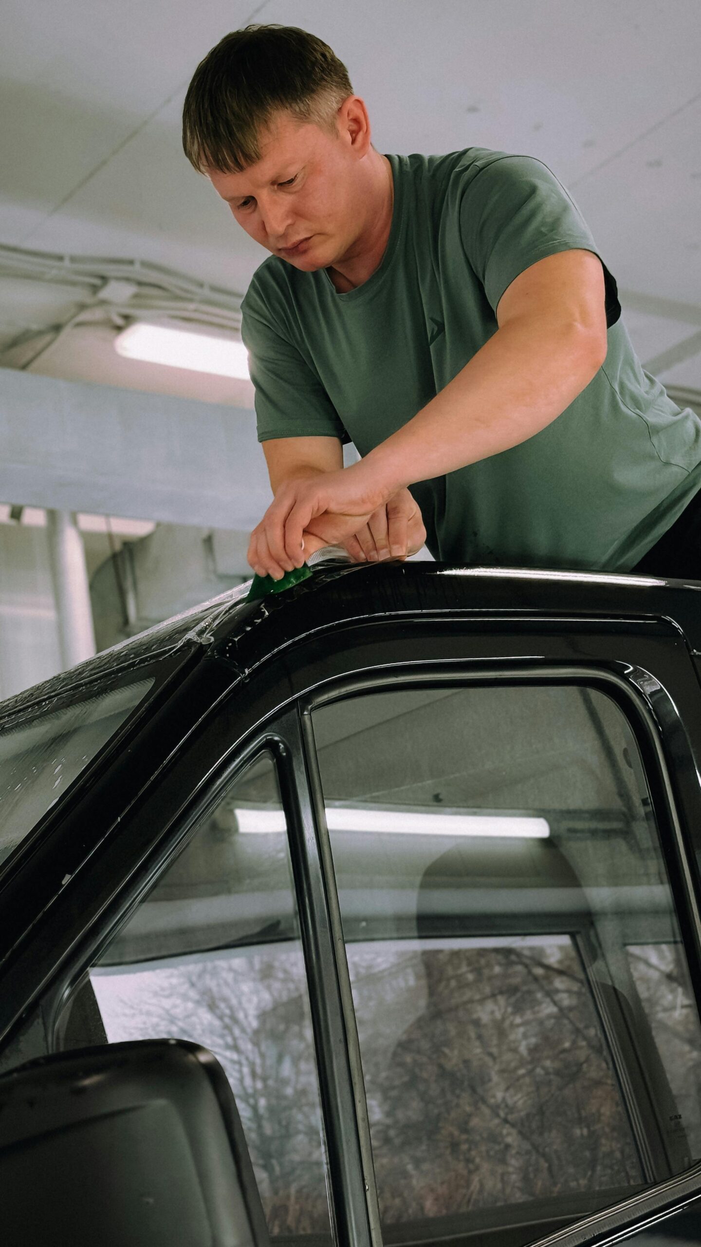 Technician applying paint protection film on a car window – Is paint protection film worth it for safeguarding your vehicle’s surfaces?