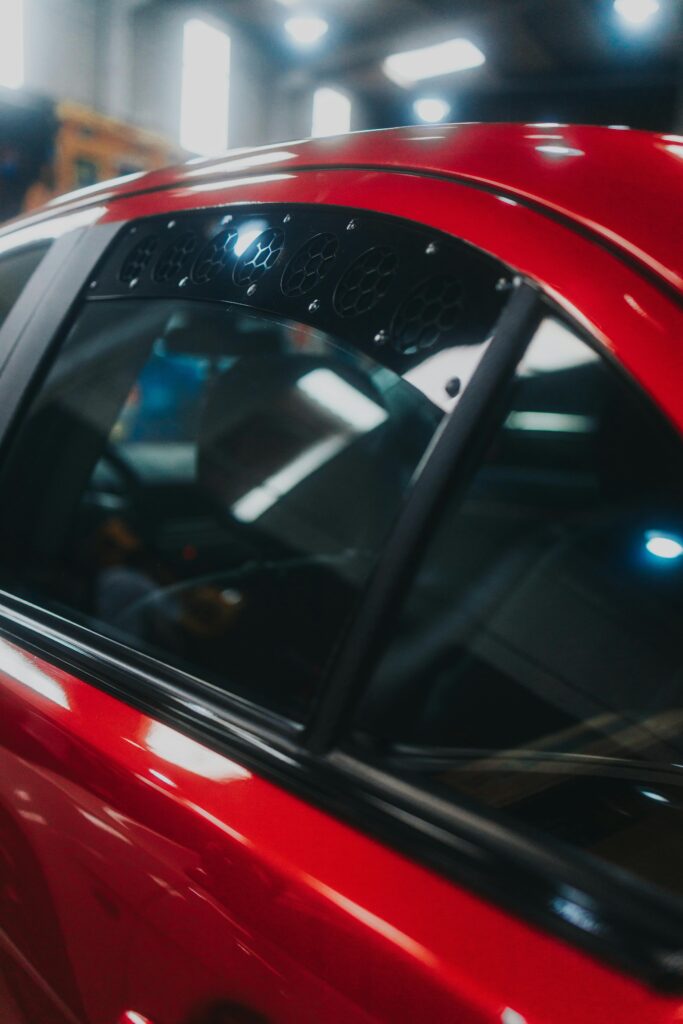 "Close-up of a car window with dark tint, reflecting the sky and surroundings
