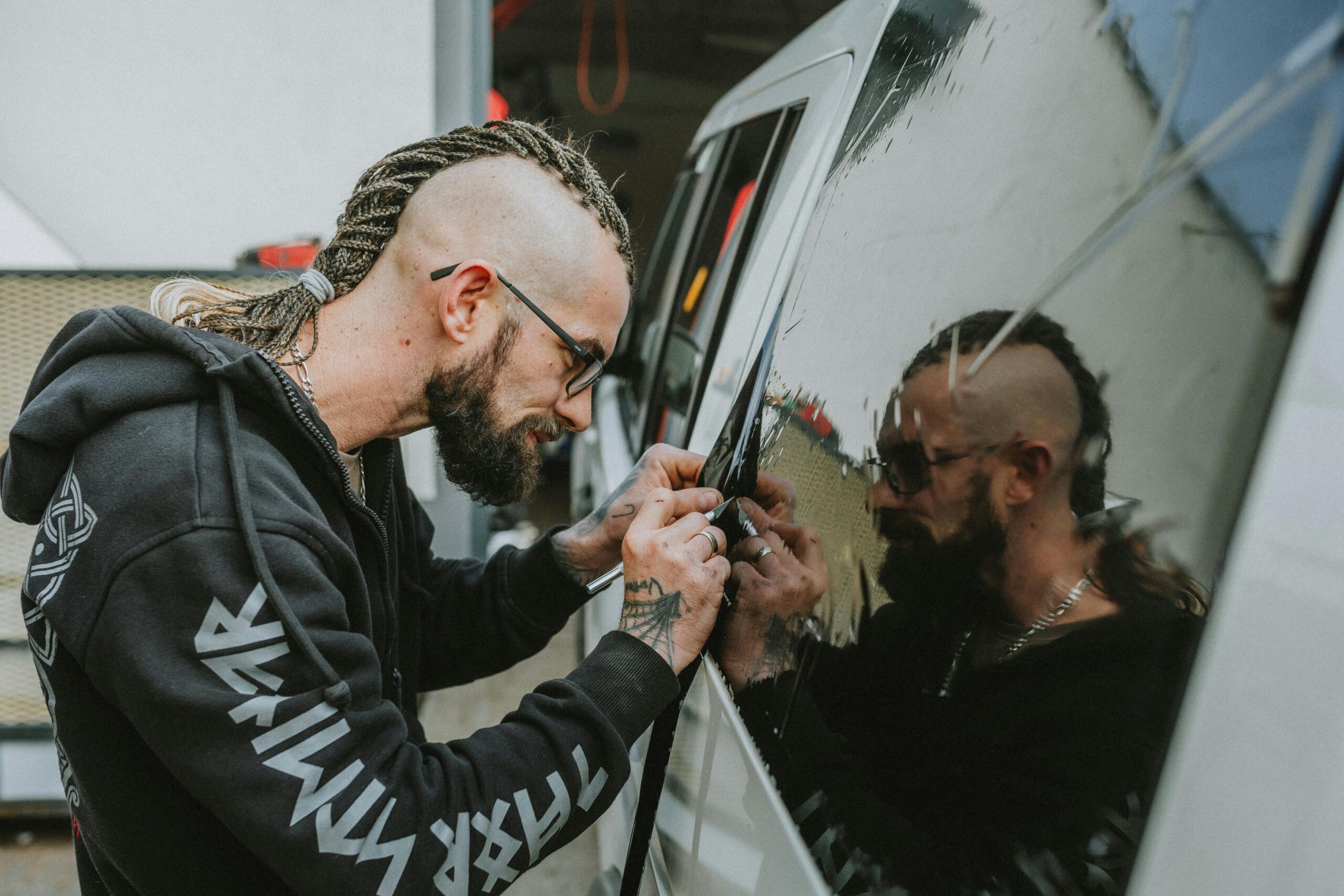 Technician peeling off film from a car window, illustrating the process and cost to remove car window tint