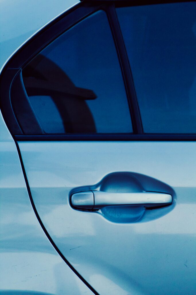 Close-up of tinted car windows in sunlight, representing factors that affect the cost to remove car window tint.